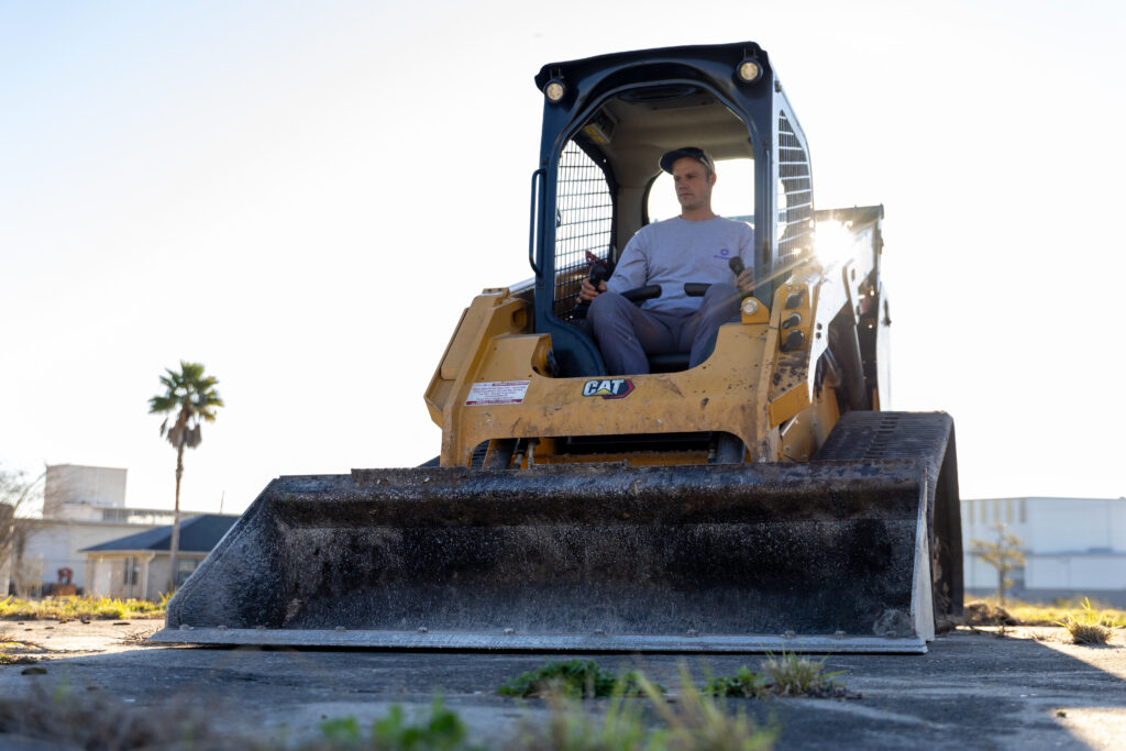 Operator in a skid steer loader preparing site for custom pool construction, emphasizing planning and financing in pool building process.