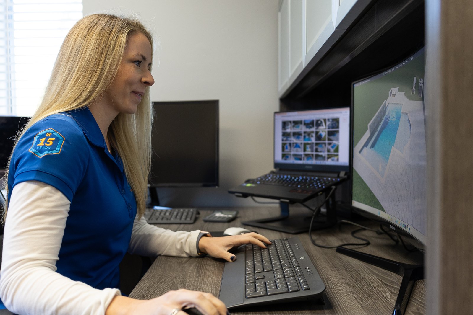 A Breakwater Construction team member setting up a new pool project on her computer at the office