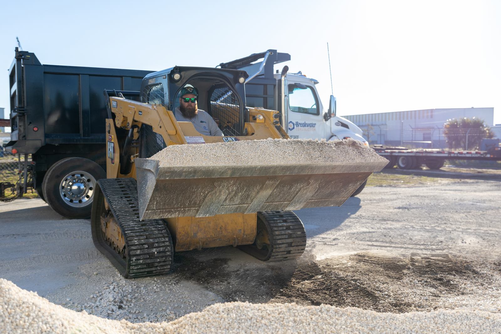 A skid steer loader and dump truck excavating a backyard for a new custom gunite pool